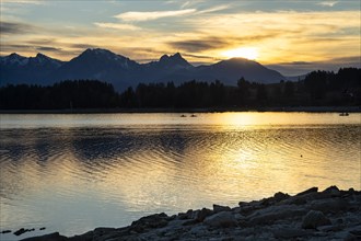 Lake Forggensee in Allgäu in autumn at sunset. Rock formations in the foreground