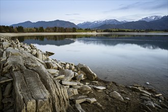 Lake Forggensee in the Allgäu in autumn after sunset. Rock formations in the foreground