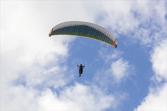 Paraglider in the sky in front of clouds