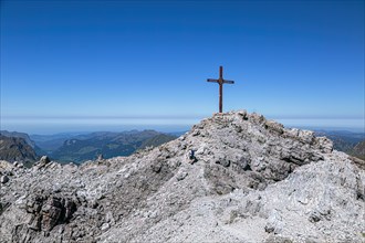 A hiker walks to the summit cross of the mountain Mohnenfluh in the Austrian Alps in Vorarlberg Lech Austria Europe