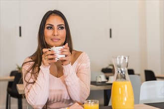Cool and relaxed casual businesswoman drinking coffee in a luxury hotel during breakfast