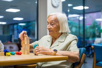 Portrait of a cheerful cute elder woman in a nursing home playing skill games
