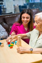 Vertical photo of a nurse helping elder people to play in a nursing home