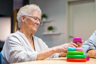 Elder woman playing skill games in a nursing home next to mates