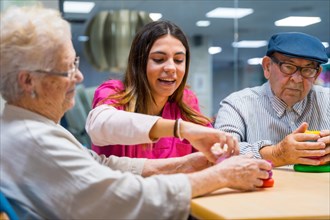 Friendly nurse supervising senior people playing skill games in nursing home