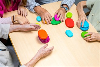 Top view of the hands of aged people playing board game in a nursing home