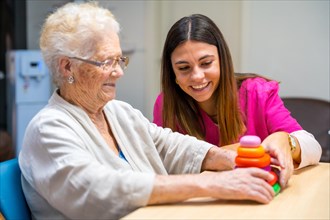 Cute nurse helping a woman to play board skill game in a nursing home