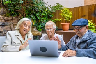 Elder people waving during a video call with laptop in a geriatric