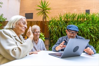 Senior people using technology in a nursing home sitting on an outdoor garden