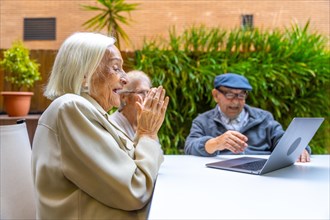 Senior people smiling and having fun using laptop in a geriatric