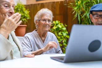 Cute senior people learning how to use a laptop in a geriatric