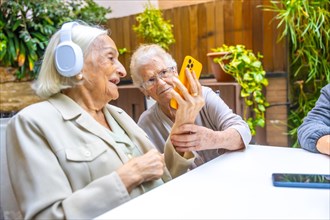 Seniors listening to music with mobile and headphones in a geriatric