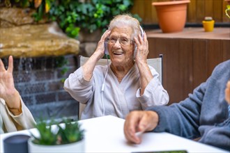 Happy seniors using headphones and having fun in a nursing home