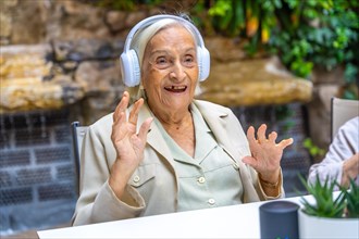 Happy woman using new technology to listening music in a geriatric