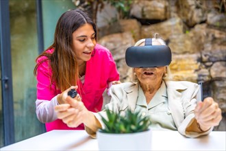 Nurse helping an elder woman to play with VR goggles in a geriatric