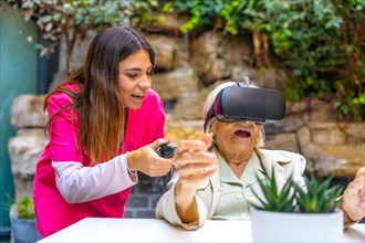 Nurse and elder woman playing with Virtual Reality goggles in a geriatric