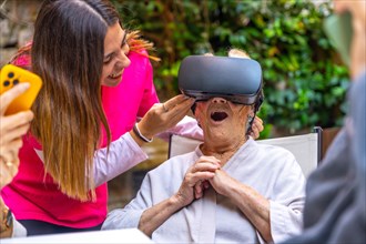 Nurse and amazed senior woman using Virtual Reality goggles in a geriatric