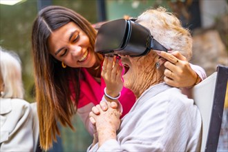 Nurse next to an amazed old woman using virtual reality goggles in a geriatric