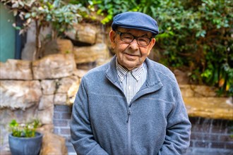 Portrait of a senior man with beret standing in a garden in a geriatric