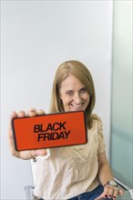 A woman showing a smartphone with Black Friday advertisement on the screen. Copy space