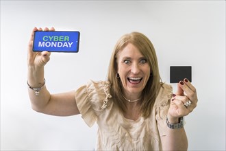 Crazy woman holding mobile phone with Cyber Monday advertisement on the screen and a credit card mock-up