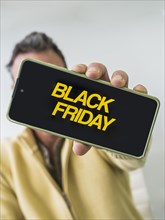 Unseen man holding mobile phone with Black Friday advertisement on the screen