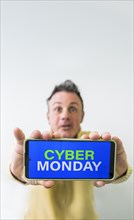 Crazy man holding mobile phone with Cyber Monday advertisement on the screen. Copy space on vertical shot