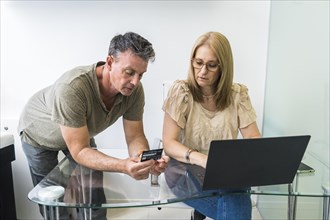 Husband and wife shopping from home using notebook and credit card