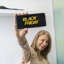 A woman showing a smartphone with Black Friday advertisement on the screen