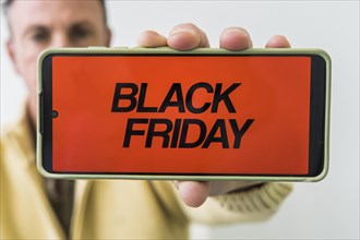 A man holding mobile phone with Black Friday advertisement on the screen