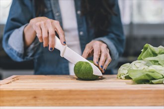 Close-up of woman chopping a vegetable in her kitchen