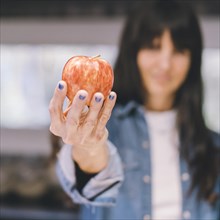 Woman showing an apple in her kitchen