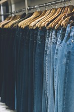 Jeans hanging on a rack in a store. Copy space. Vertical shot