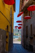City Street in Porto Ceresio with Hanging Umbrellas with Lake View in a Sunny Summer Day in Porto Ceresio