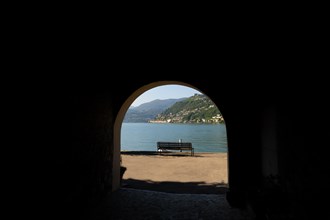 Old Beautiful Street Tunnel with Arch and a Bench From Brusino Arsizio on the Waterfront in a Sunny Summer Day and with Lake Lugano and Mountain View over Morcote