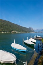 Port with Boats in Brusino Arsizio on the Waterfront in a Sunny Summer Day with Blue Sky on Lake Lugano and Mountain in Brusino Arsizio