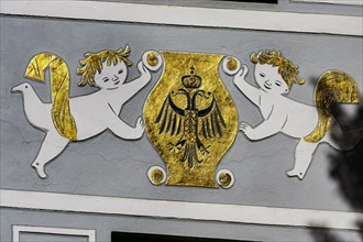 Fresco with golden coat of arms and double-headed eagle with crown on grey facade