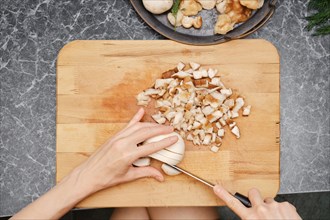 Top view of female hands cutting champignon on wooden cutting board