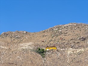 Small yellow monastery in rugged mountain slopes