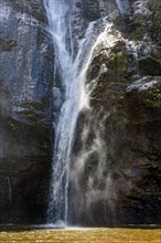 Waterfall water running down dark rocks lit by the sun in the state of Minas Gerais