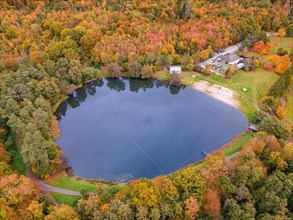 The leaves of the trees around the Hattsteinweiher pond near Usingen in the Taunus Mountains are beginning to turn autumnal yellow and orange.