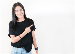 Smiling teenage girl pointing side with hand. Cheerful latin girl pointing an offer isolated. Happy teenager pointing a promo isolated