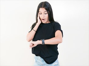 Surprised young woman looking at wrist watch. Worried young woman looking at her watch isolated