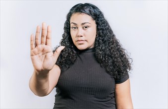 Close up of woman gesturing stop with the palm of hand isolated. People gesturing stop isolated. Latin woman gesturing stop with palm hand isolated