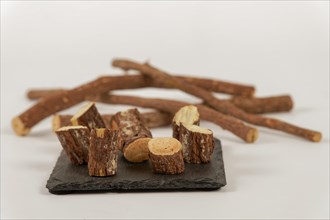 Group of sliced natural licorice roots on a black slate and white background