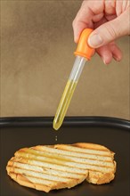 Woman pours olive oil on toast with an dropper because of excessive oil prices