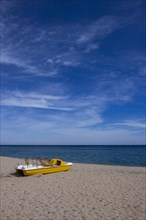 Yellow pedal boat on the beach with blue sky and blue sea