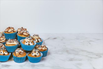 Muffins in blue ramekins with chocolate icing and sugar sprinkles