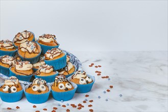 Muffins in blue ramekins with chocolate icing and sugar sprinkles