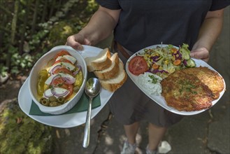 A waiter serves vegetarian food in a garden restaurant